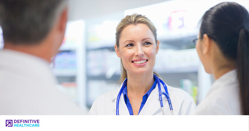 A smiling clinician talks with two of her colleagues.