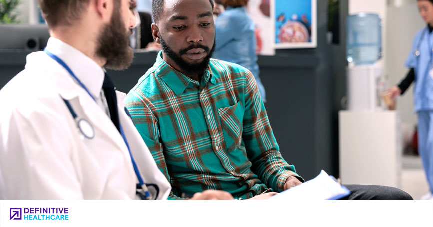 A physician talks to a patient while examining a form. 