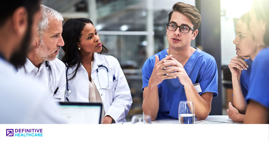 A team of clinicians sit around a table and talk.