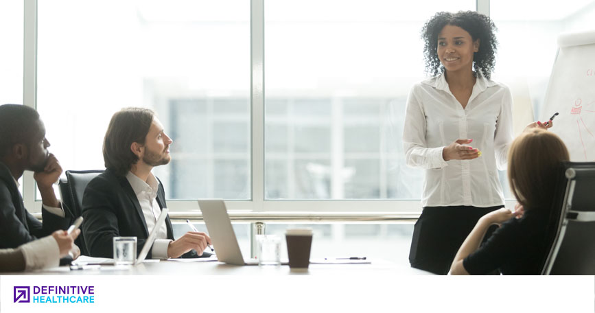 A woman gives a presentation to professionals in a conference room.