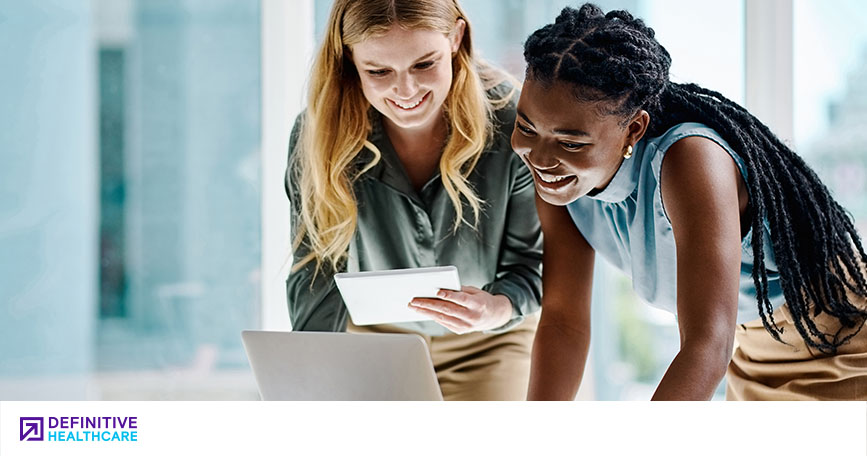 Two smiling women look down at a computer screen