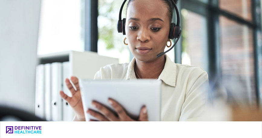 A professional wears a headset while looking at a tablet.