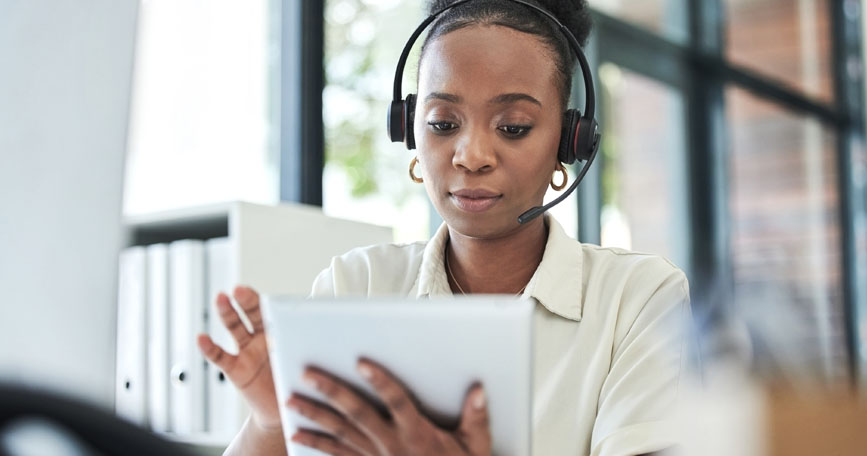 A professional wears a headset while looking at a tablet.