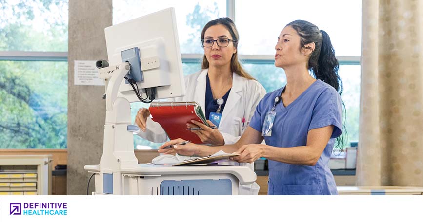 Two healthcare professionals work at a computer station.