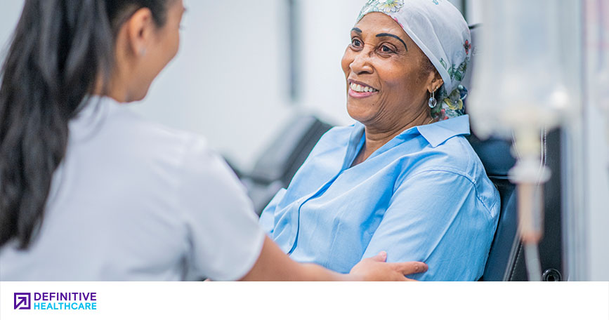 A patient smiles while a healthcare professional prepares her for a procedure.