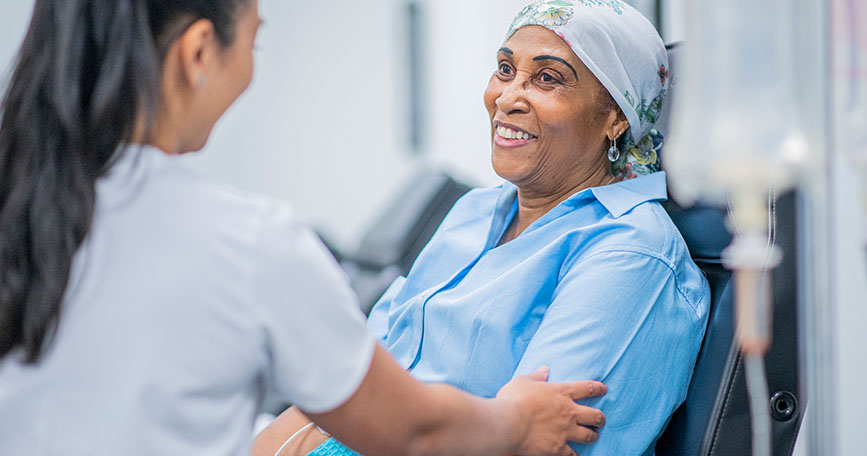 A patient smiles while a healthcare professional prepares her for a procedure.