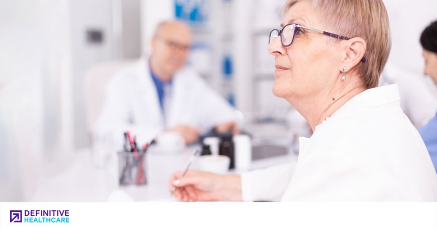 A clinician takes notes and listens during a meeting.