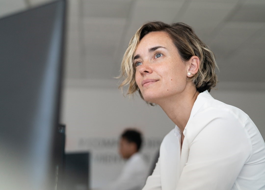 A healthcare professional smiles while near a computer screen.