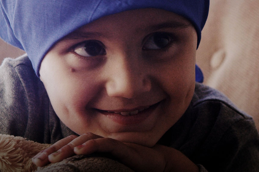 A smiling pediatric patient wearing a head cover.