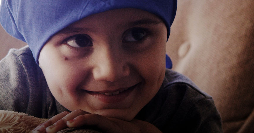 A smiling pediatric patient wearing a head cover.