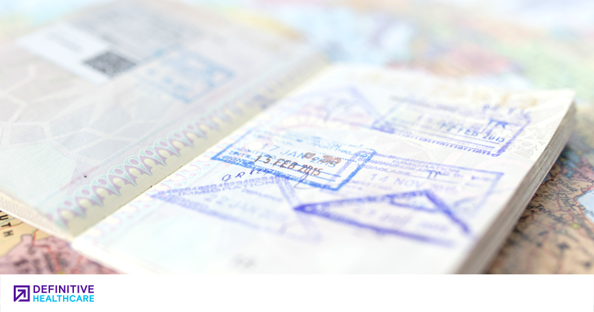 An open page of a passport with stamps sits on a map