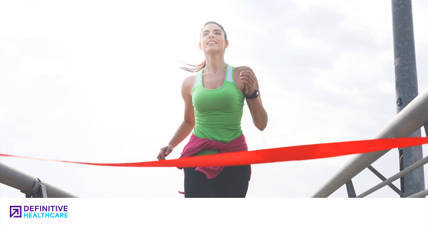 A woman in running attire crosses the finish line at a race.