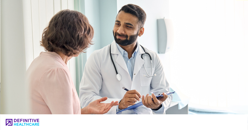 A doctor takes notes while speaking to a patient.