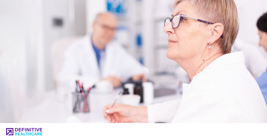 A clinician takes notes and listens during a meeting. 