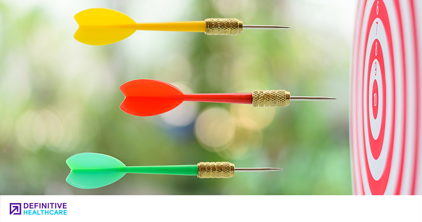 Yellow, red and green darts flying towards a dartboard