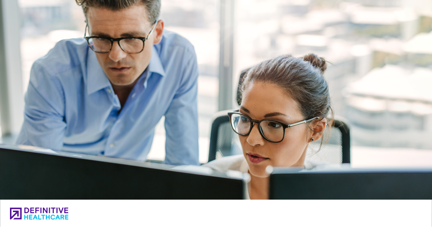 A man and a woman look at a computer monitor together.