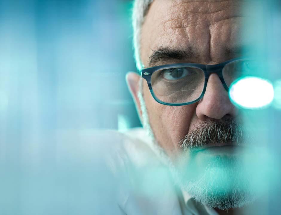 A man wearing eyeglasses stares into the camera.