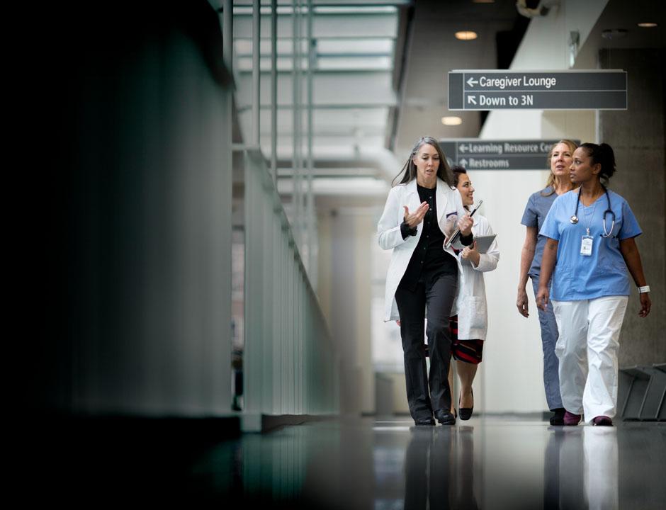 Four healthcare professionals walking together in a hallway.