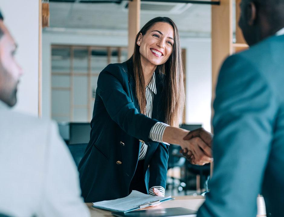 woman and man standing and shaking hands over a table