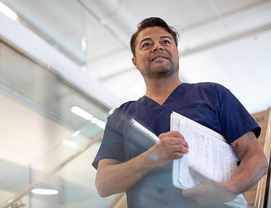 healthcare provider walking down stairs while holding paperwork under his arm